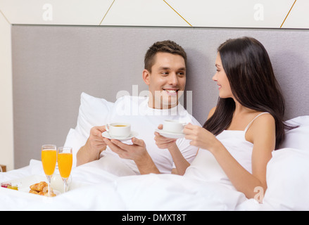 smiling couple having breakfast in bed in hotel Stock Photo