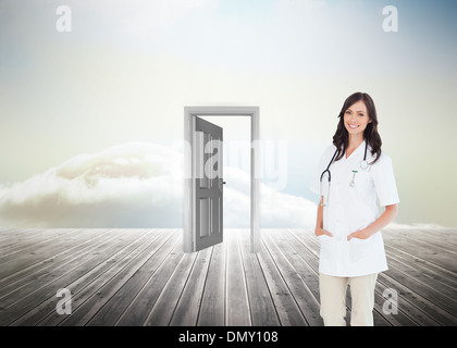 Composite image of confident and smiling woman doctor standing in front of the window Stock Photo