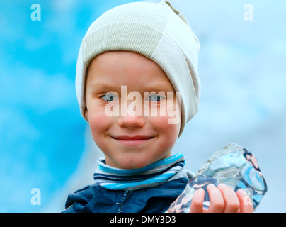 Portrait happy boy with piece of ice in hand on Nigardsbreen glacier background (Norway) Stock Photo