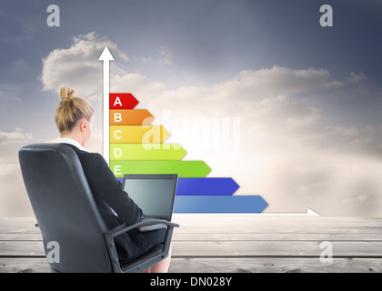 Composite image of businesswoman sitting on swivel chair with laptop Stock Photo