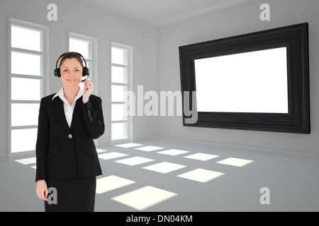 Composite image of good looking woman in suit using headphones and posing Stock Photo