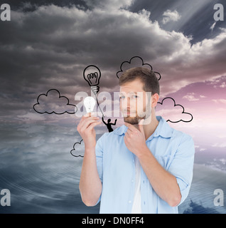 Composite image of handsome model holding a bulb Stock Photo