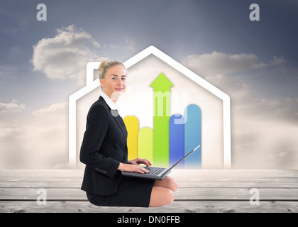 Composite image of businesswoman using laptop Stock Photo
