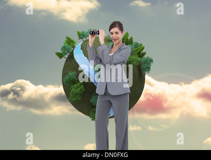 Composite image of businesswoman posing with binoculars Stock Photo