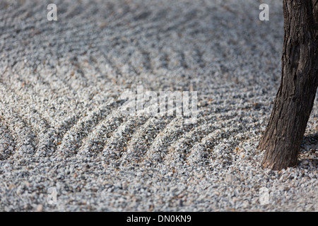 Peaceful Zen garden with raked sand and single tree trunk.  Calm image, strong background, and copy space. Stock Photo