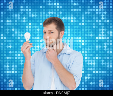 Composite image of handsome model holding a bulb Stock Photo