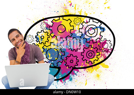 Composite image of thinking man sitting on floor using laptop and smiling Stock Photo