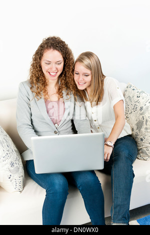 Two young smiling women using laptop computer at home Stock Photo