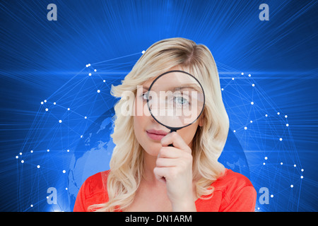 Composite image of fair-haired woman looking through a magnifying glass Stock Photo