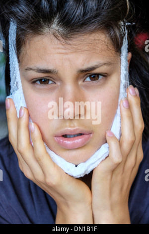 Teenager recovering from removal of wisdom teeth using a cold pack Stock Photo