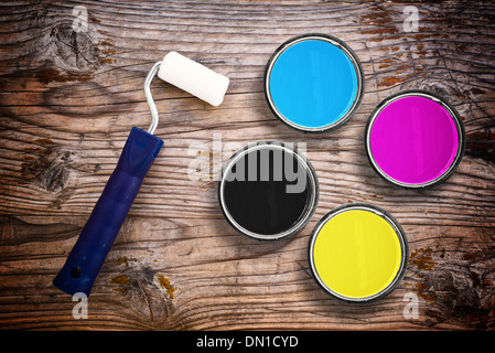 Metal tin cans with four process CMYK colors with paint roller. Printing industry conceptual background. Stock Photo