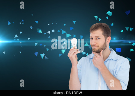 Composite image of handsome model holding a bulb Stock Photo