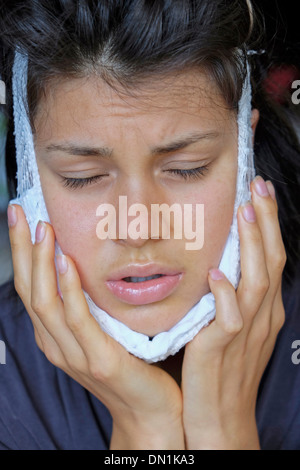 Teenager recovering from removal of wisdom teeth using a cold pack Stock Photo