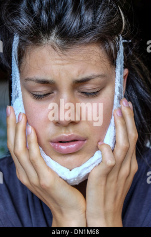 Teenager recovering from removal of wisdom teeth using a cold pack Stock Photo