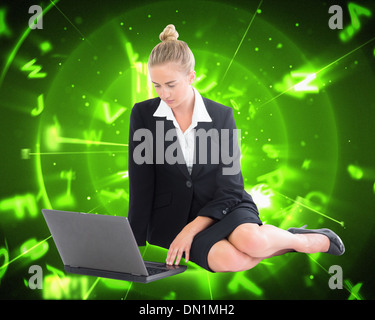 Composite image of businesswoman using laptop Stock Photo