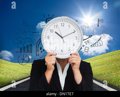 Composite image of businesswoman in suit holding a clock Stock Photo