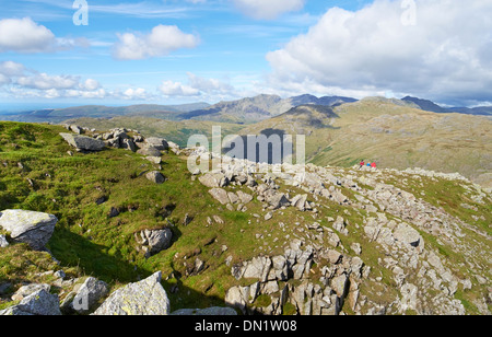 A family resting on the summit of Great Carrs with Scafell Pike in the distance. Stock Photo