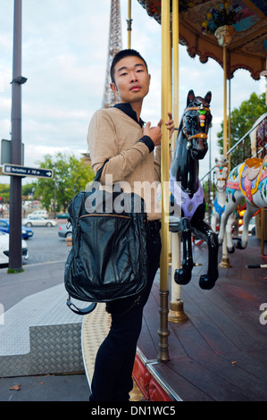 Paris, France, Young Chinese Man, Standing on French Merry-go-Round, "Round About", Mange, Holding Bag Stock Photo