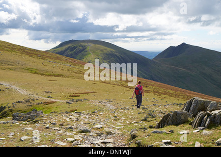 A hiker walking off Great Carrs towards the Old Man of Coniston and Dow Crag in the Lake District. Stock Photo