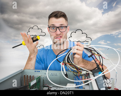 Composite image of portrait of confused it professional with screw driver and cables in front of ope Stock Photo