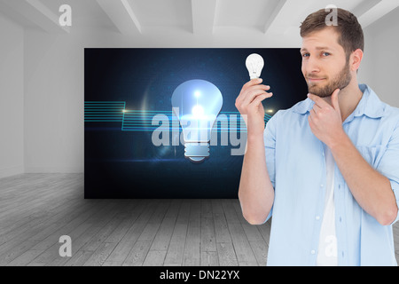 Composite image of handsome model holding a bulb Stock Photo