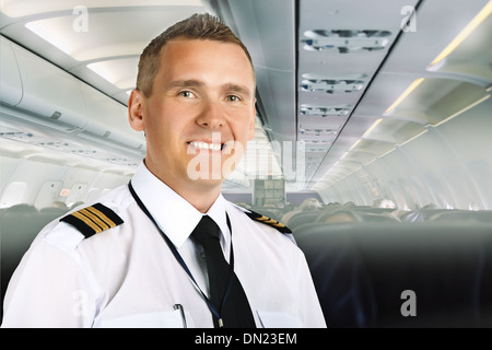Airline pilot wearing uniform with epaulettes on board of passenger aircraft. Stock Photo