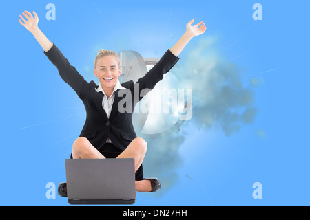 Composite image of businesswoman sitting in front of laptop with arms up Stock Photo