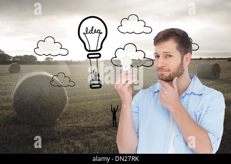 Composite image of handsome model holding a bulb Stock Photo