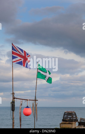 Union and Devon flags fly as eels and a buoy hang from a frame by the sea at Beesands, Devon. Lobster pots complete the scene. Stock Photo