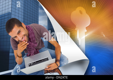Composite image of thoughtful man sitting on floor using laptop and smiling at camera Stock Photo