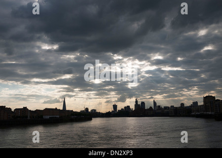 Sunlight breaking through clouds over the River Thames and the City skyline from East London, UK.
