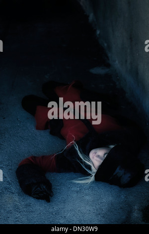 a woman in a red coat is lying in a dark tunnel Stock Photo