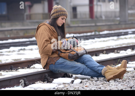 Photo of beautiful young woman with vintage camera sitting on the	 railway. Stock Photo