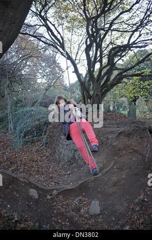 An 11 year old girl swings on a rope Stock Photo