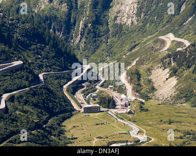 The railway station and surrounding buildings of Gletsch in Swiss alps, the Furka pass and Grimsel pass roads rising steeply Stock Photo