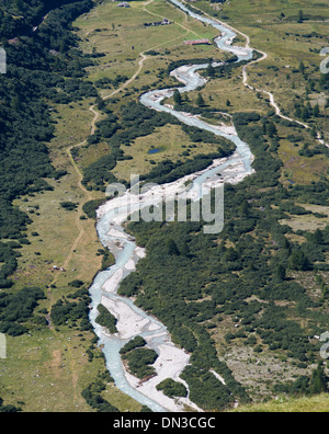 Areal view of a river with opaque glacier water and footpath on a green valley plain near  Gletsch in Swiss alps Stock Photo