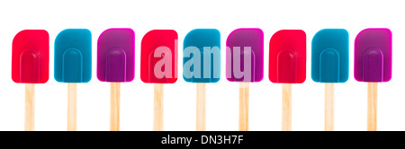 A panoramic image of three different colored spatulas with wooden handles. Stock Photo
