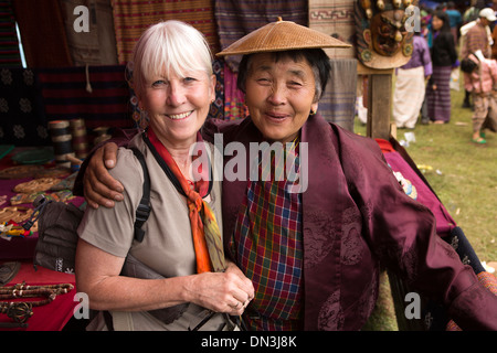 Bhutan, Thangbi Mani Lhakang Tsechu Festival, western visitor with souvenir stalholder Stock Photo