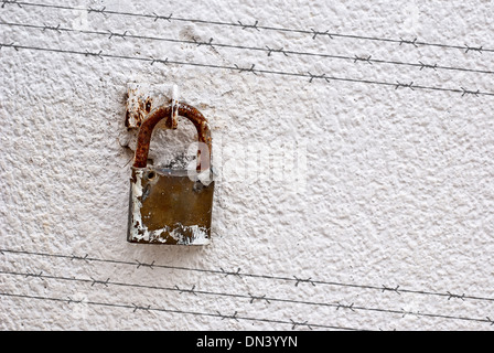 Shadow of barbed wire on wall with padlock Stock Photo