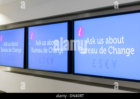Screens in a tourist information office asking visitors to ask about Bureau de Change facilities