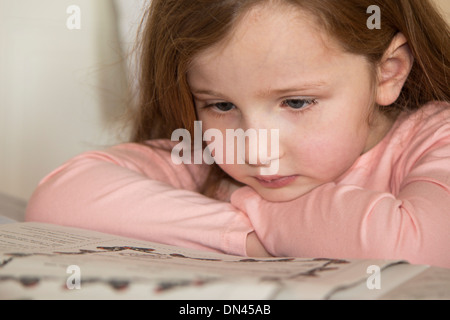 Young girl in pink reading a story book Stock Photo