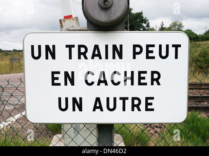 Warning sign at French railway level crossing Un Train Peut En Cacher Un Autre, one train can hide another Stock Photo