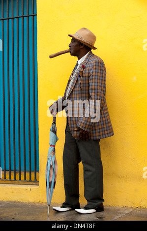 Profile man of color black smiling holds cigar in hand umbrella plaid jacket traditional dress in Havana Cuba street tourism Stock Photo