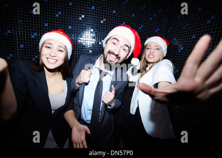 Portrait of joyful colleagues in Santa caps dancing at Christmas party Stock Photo