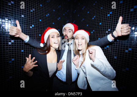Portrait of joyful colleagues in Santa caps having fun in nightclub Stock Photo