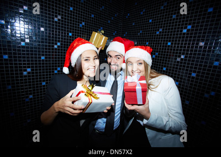 Portrait of joyful colleagues in Santa caps having fun in nightclub Stock Photo