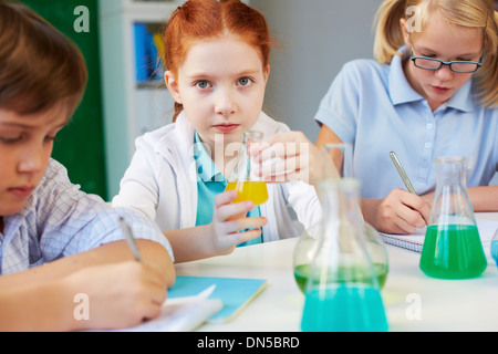 Three children working with chemical liquids at lesson in school lab Stock Photo