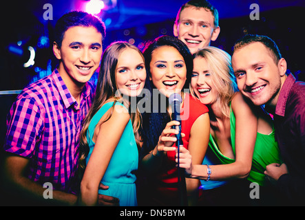 Portrait of happy girls and guys singing in microphone in the karaoke bar Stock Photo