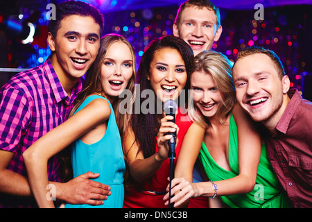 Portrait of happy girls and guys singing in microphone in the karaoke bar Stock Photo