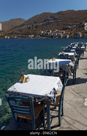 Tables and chairs of a restaurant on the seafront, Symi, Symi Island, Dodecanese, Greece Stock Photo